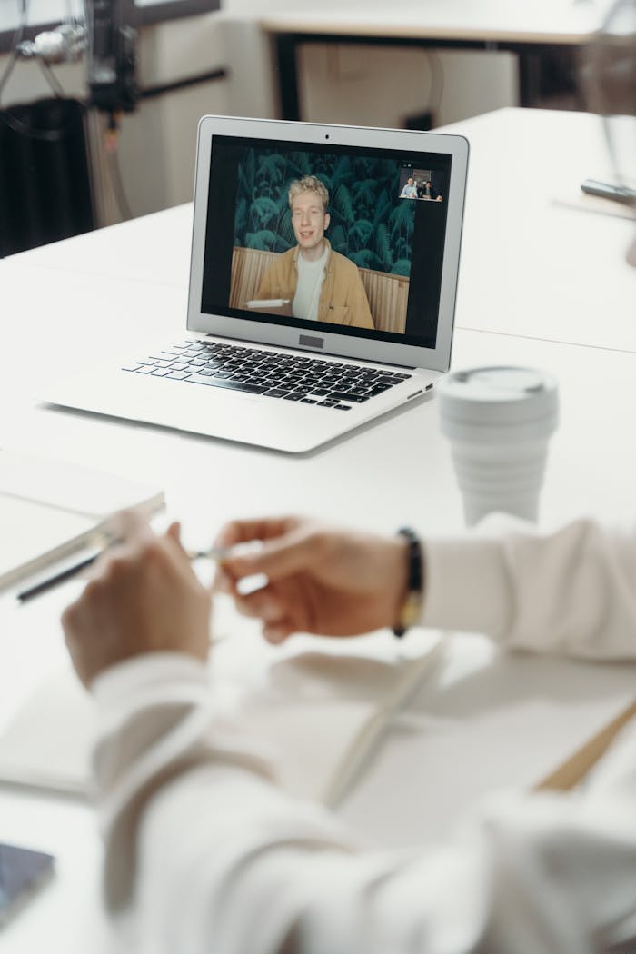 Professional virtual meeting with focus on laptop screen showing a video call participant.