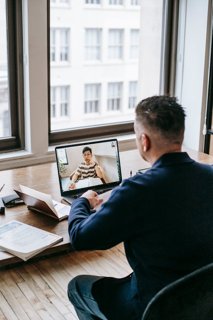Businessman engaged in a video call at a wooden desk in a bright office.